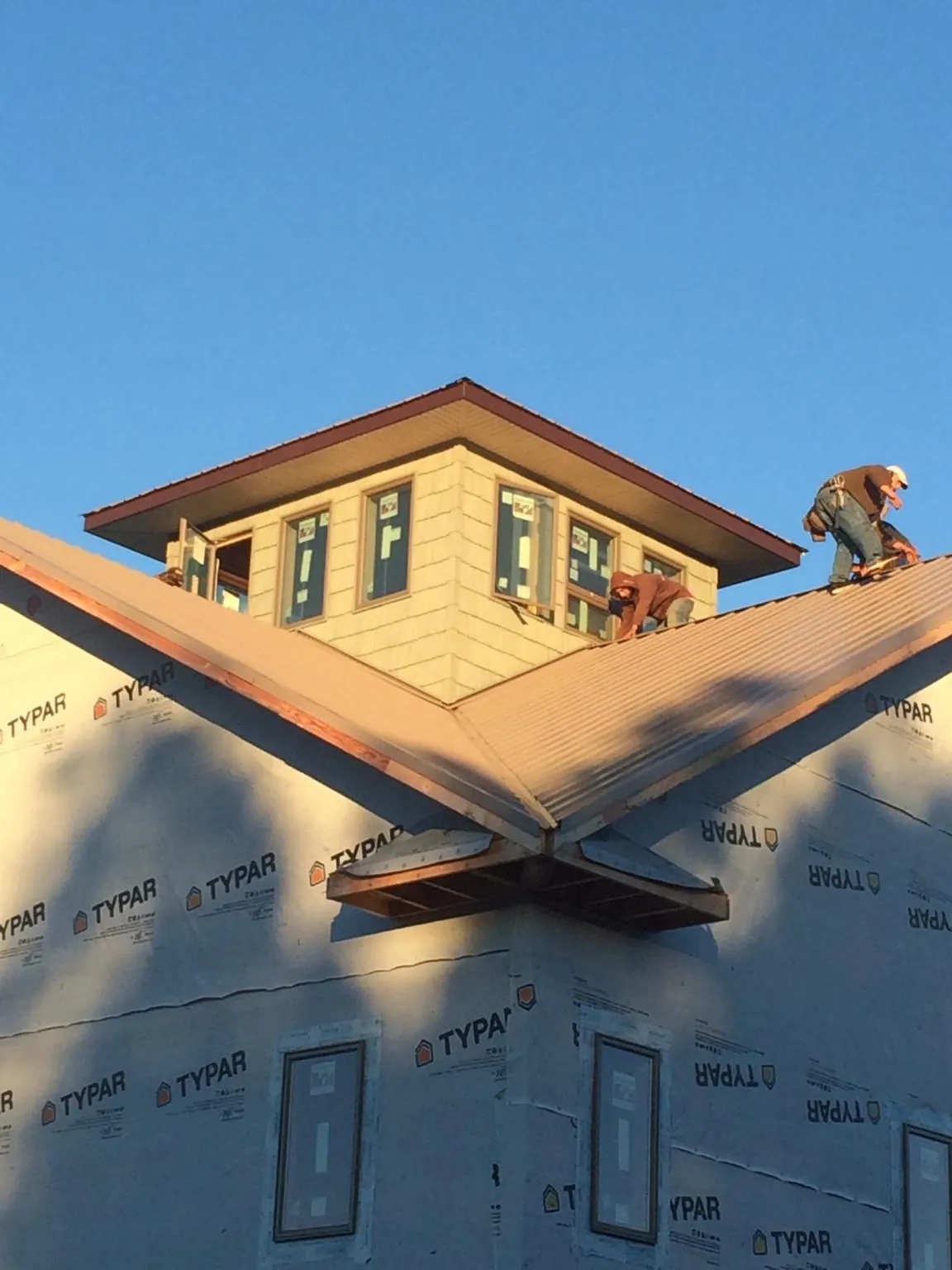Roofers working around a rooftop cupola on a new metal roof at sunset — Roof Waterproofing in Pontiac by Roofing Brothers